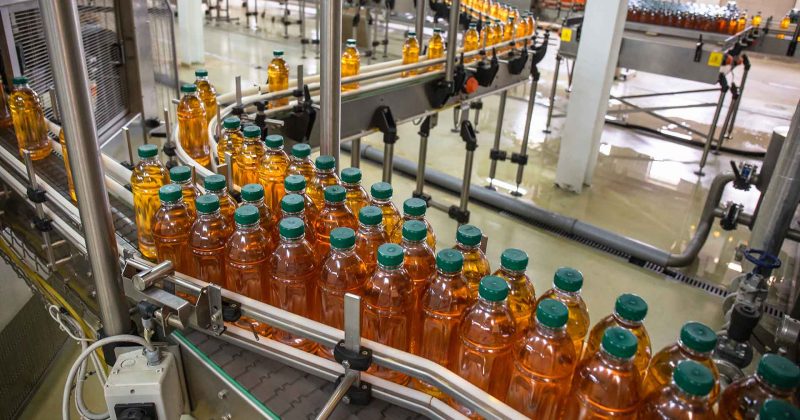 packaged, unlabeled apple juice on a production line